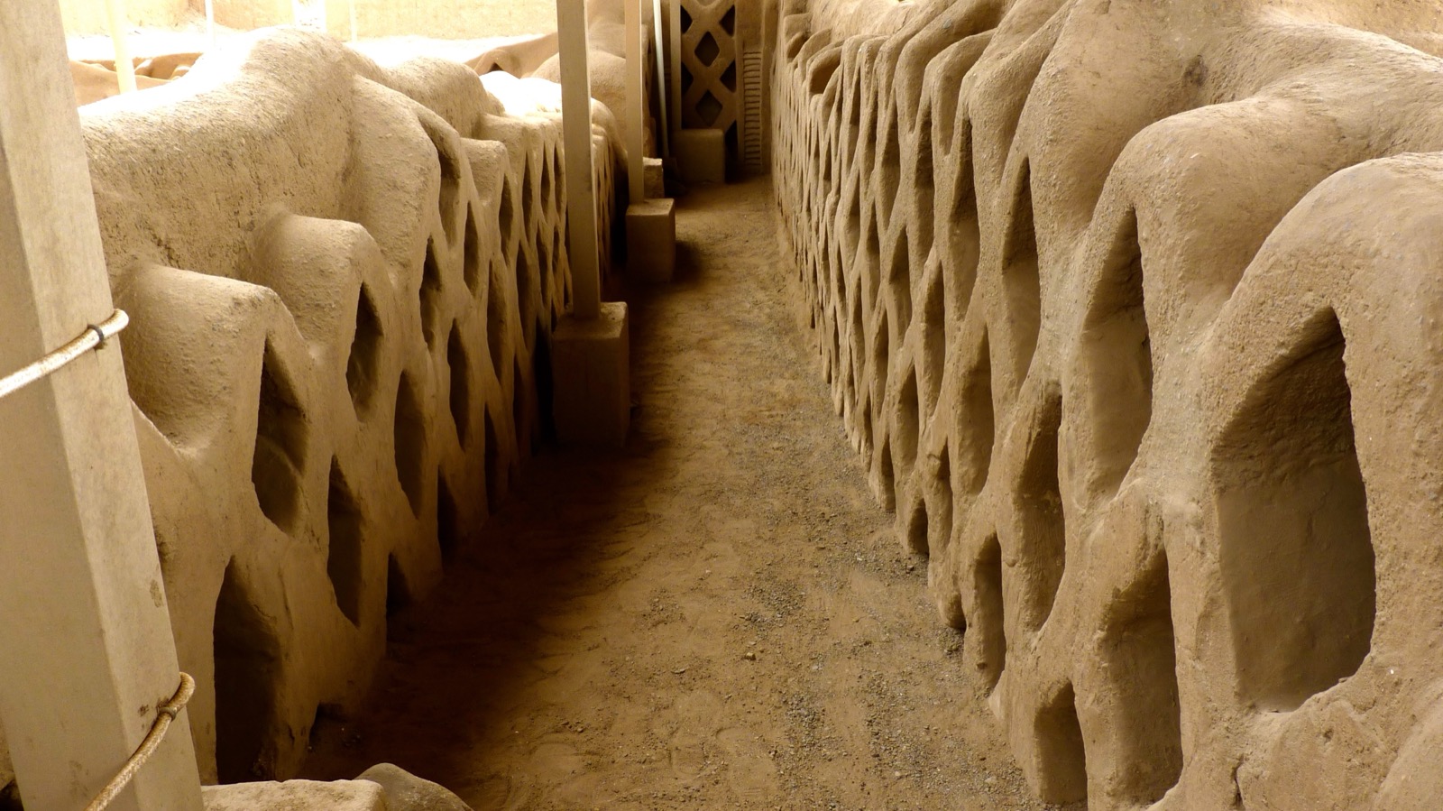 Innenkorridor der Lehmziegel-Stadt Chan Chan bei Trujillo, Peru: hohe Adobe-Wände mit charakteristischen, in den Lehm gearbeiteten Nischen- und Gittermustern der Chimu-Kultur.