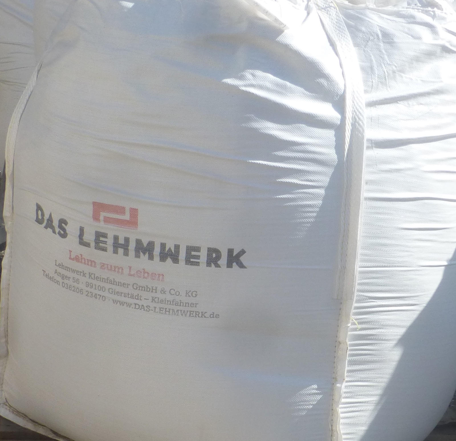 Frisch aufgetragener naturfarbener Lehmputz an einer Innenwand, repraesentativ fuer industriell gefertigte Lehmbaustoffe